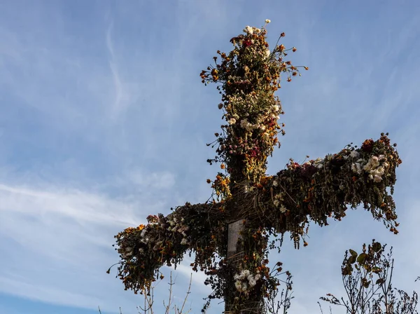 Krásný dřevěný kříž na vesnici zdobené květinami — Stock fotografie