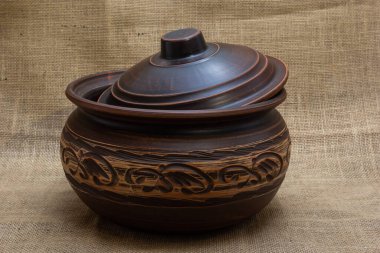 Turuncu-kahverengi renkli seramik sofra takımı. Kumaşın arka planında doğal renklerle beyaz desenli..