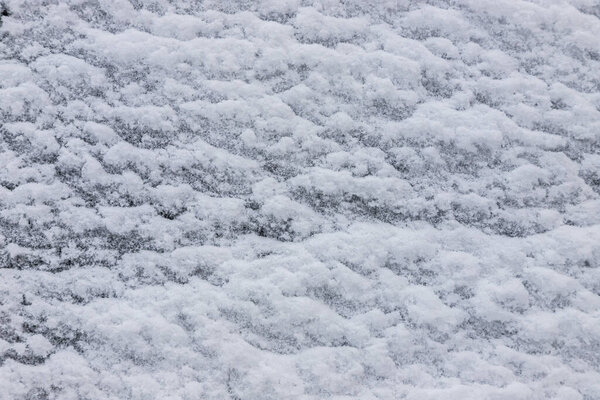 Beautiful winter background with snowy ground. Natural snow texture. Wind sculpted patterns on snow surface.