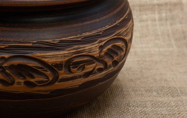 Turuncu-kahverengi renkli seramik sofra takımı. Kumaşın arka planında doğal renklerle beyaz desenli..