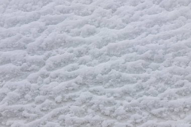 Karlı zemini olan güzel bir kış arkaplanı. Doğal kar dokusu. Kar yüzeyinde rüzgar şekilli desenler.