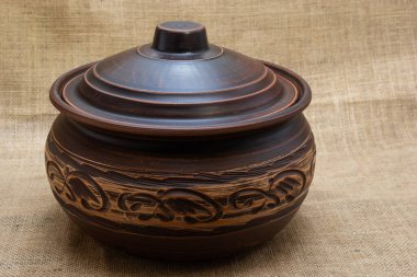 Turuncu-kahverengi renkli seramik sofra takımı. Kumaşın arka planında doğal renklerle beyaz desenli..