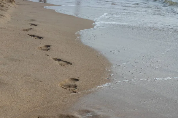 Fußabdrücke Sandstrand Fußabdrücke Sand Gegen Eine Meereswelle Fußspuren Einem Sonnigen — Stockfoto
