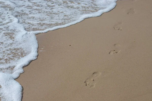 Fußabdrücke Sandstrand Fußabdrücke Sand Gegen Eine Meereswelle Fußspuren Einem Sonnigen — Stockfoto