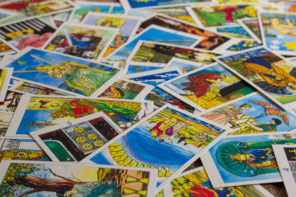 Background with pile of the tarot cards, the major arcana deck. Fortune telling seance or black magic ritual. Scary still life with occult and esoteric symbols. Halloween or divination rite.