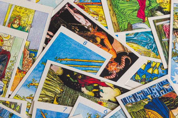 Background with pile of the tarot cards, the major arcana deck. Fortune telling seance or black magic ritual. Scary still life with occult and esoteric symbols. Halloween or divination rite.