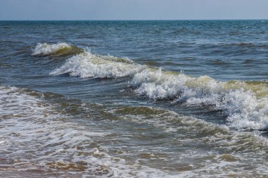 Sprey ve köpükle kıyıya yakın deniz dalgaları.