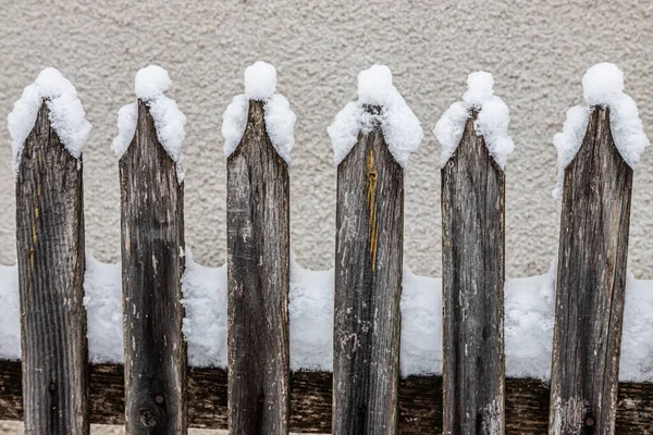 An old wooden picket fence in the village in winter. Snow on the fence. Selective focus.