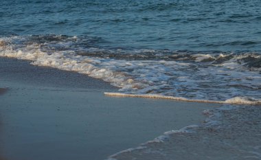 Büyük ve güçlü bir turkuaz fırtına dalgası. Beyaz köpük damlaları kıyıya vuruyor ve kırılıyor..