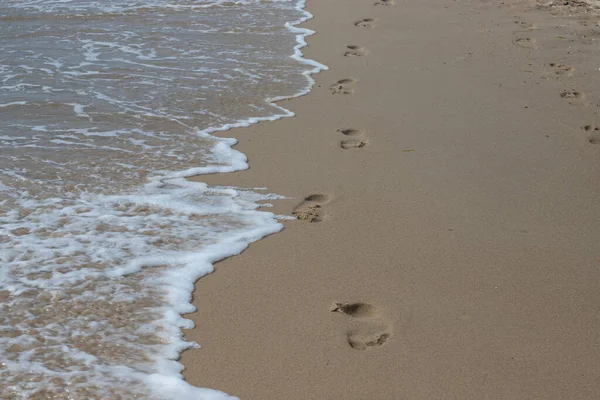 Kumsalda Ayak Izleri Kumdaki Ayak Izleri Bir Deniz Dalgasına Karşı — Stok fotoğraf