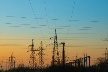 Elektrik direği, fotoğrafta bir elektrik direği ve mavi gökyüzüne bağlı kablolar var..