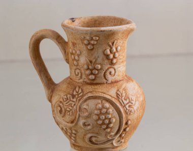 Beyaz arkaplanda kabzalı kil sürahi.