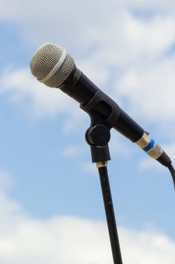 Gökyüzü arka planında mikrofon. Mikrofon caddede duruyor. Konsept - sokak müziği. Ses ekipmanı.