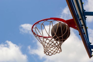 Kalede bir basket topu. Uçan top ringde. Bir spor oyunu. Kavramsal: Zafer, başarı, hedefi vurmak, spor. Başarılı bir top atma..