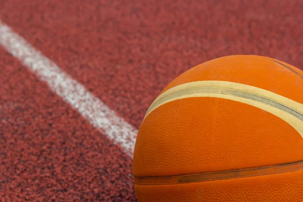 Orange ball for basketball lying on the sport court.Sport red court outdoor .Copy space.Top view.