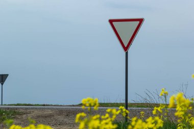 İşaret, arka planda kırsal bir kavşakta otobandan çıkarken şoföre yol verir.