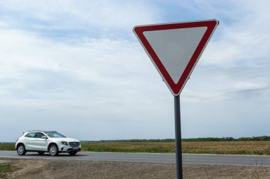 İşaret, yoldan geçen bir arabanın arka planında kırsal bir kavşakta otobandan çıkarken şoföre yol verir..