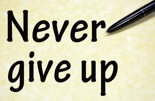 Never give up title written with pen on paper — Stock Photo, Image