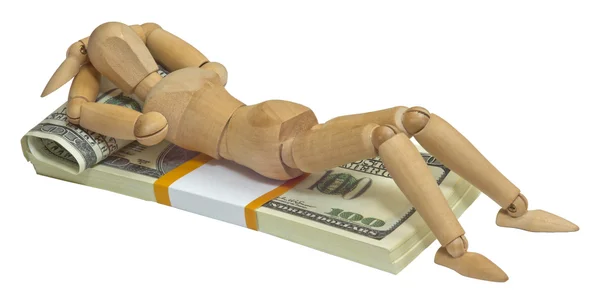 Wooden man lying on a pack of dollars are on the bed — Stock Photo, Image