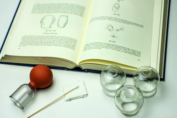 Cupping glasses with textbook — Stock Photo, Image