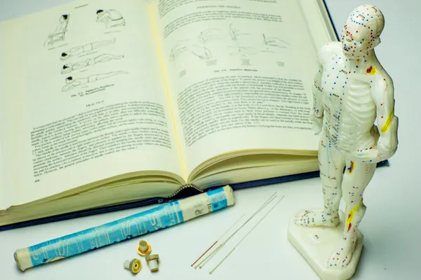 Acupuncture needles and textbook — Stock Photo, Image