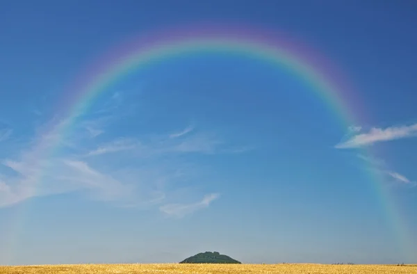 Cereal field with hill and rainbow — Stock Photo, Image