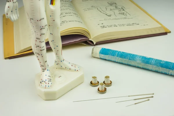 Acupuncture needles, model, textbook and moxa roll — Stock Photo, Image