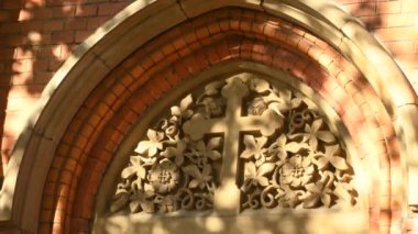 Üzerinde haç ve dans eden yapraklardan gölgeler olan eski kilise kapısı.