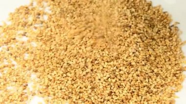 Sesam tohumları yakın planda bir sehpanın üzerine düşüyor. 