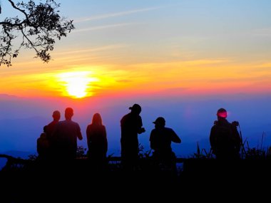 Turistler gün batımının dağın zirvesine dokunuşunu izlemek için bekliyorlar. İnsanların silueti. grup insan.