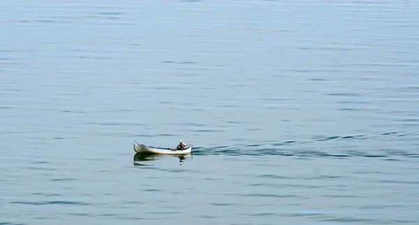 Una barca con un pescatore galleggia sulla superficie dell'acqua — Foto Stock