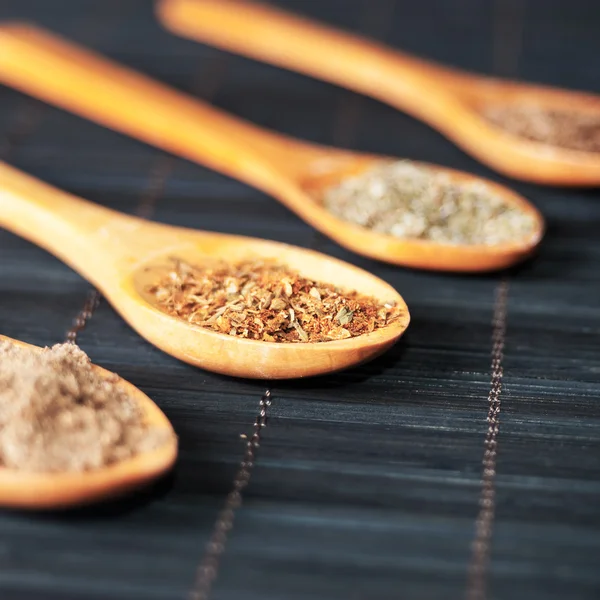 Varias especias en cucharas de madera — Foto de Stock