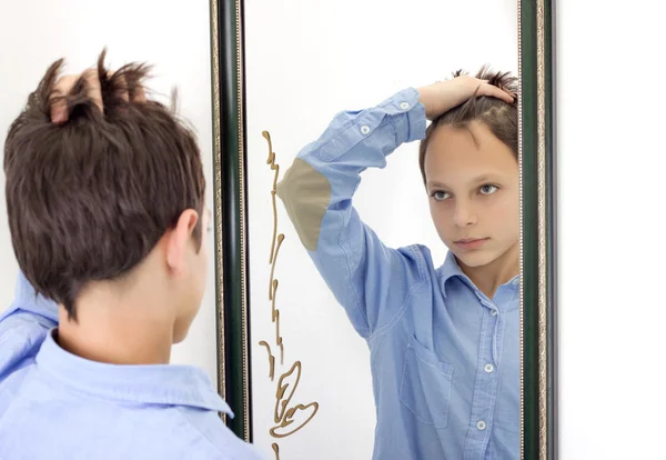Мальчик расчесывает волосы в зеркале — стоковое фото