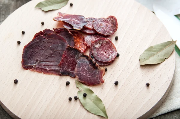 Saucisse de salami sèche tranchée sur une planche de bois — Photo