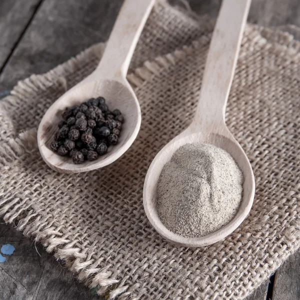 Black and white pepper on wooden background — Stock Photo, Image