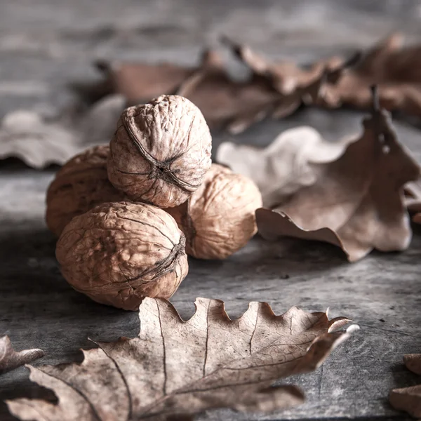 Nueces y hojas sobre mesa de madera —  Fotos de Stock