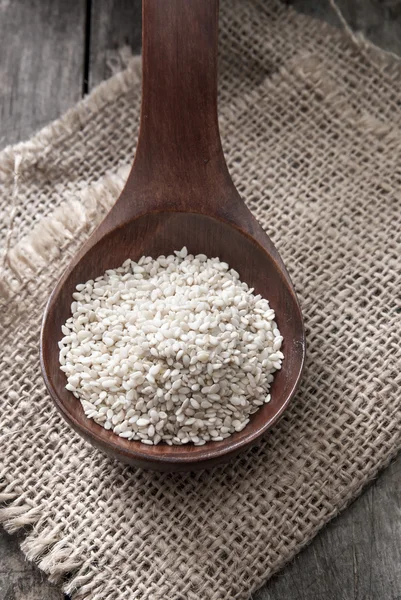 Organic natural sesame seeds on wooden spoon — Stock Photo, Image