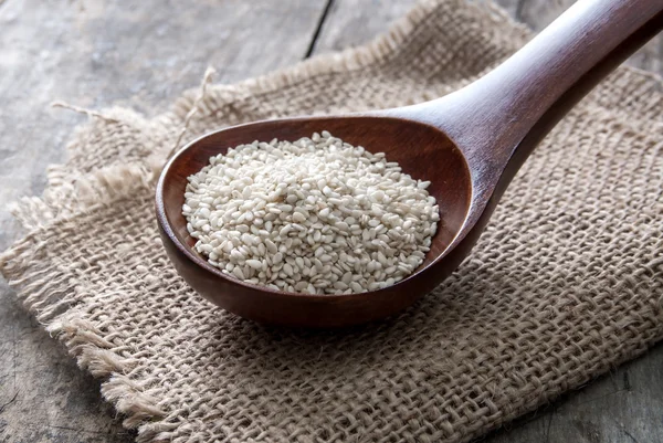 Organic natural sesame seeds on wooden spoon — Stock Photo, Image