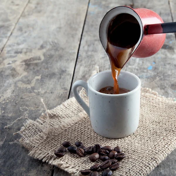 Cup of coffee and  pot  on wooden background — Stock Photo, Image