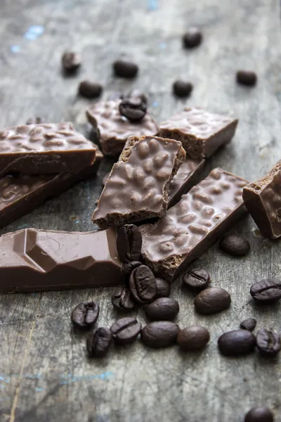 Barras de chocolate e grãos de café na mesa de madeira — Fotografia de Stock