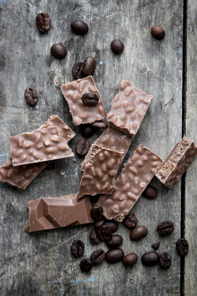 Шоколадные батончики и кофейные зерна на деревянном столе — стоковое фото