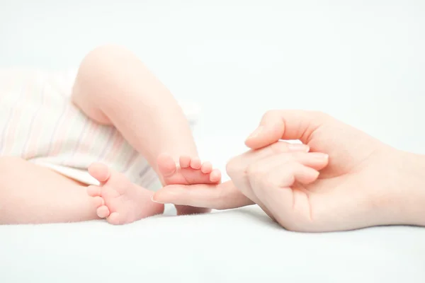 Kleine baby voeten en de hand van de moeder — Stockfoto