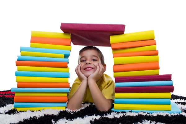 Uśmiechnięty chłopiec z stos książek — Zdjęcie stockowe