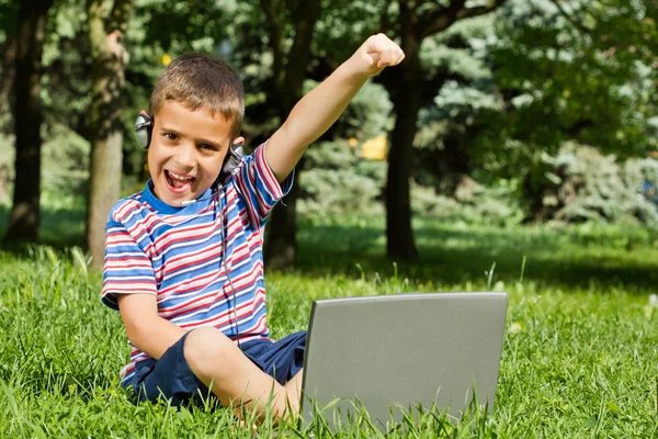 Pojken med sin laptop utomhus i parken — Stockfoto