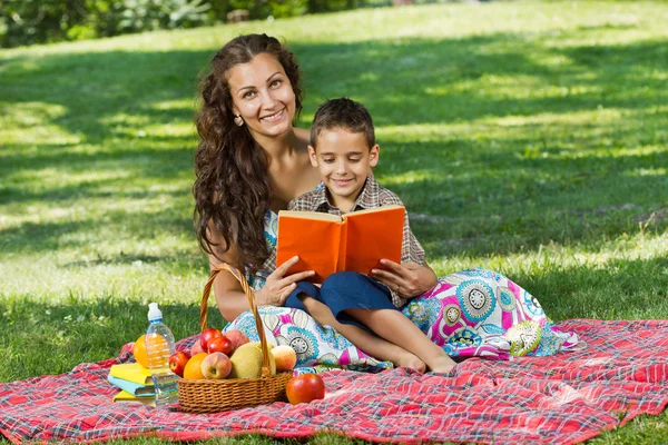 Moeder en kleine jongen in park lezen boek samen — Stockfoto