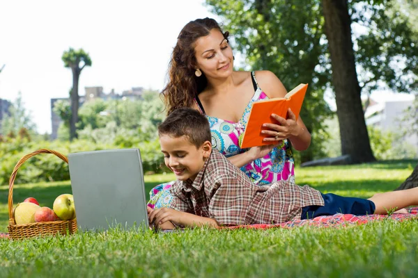 Mère lisant un livre dans le parc — Photo