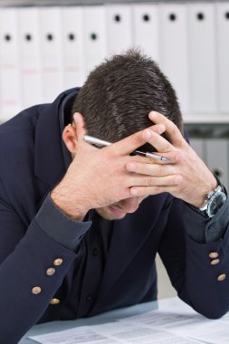 koyu elbiseli ofis masa başında oturup endişeli işadamı