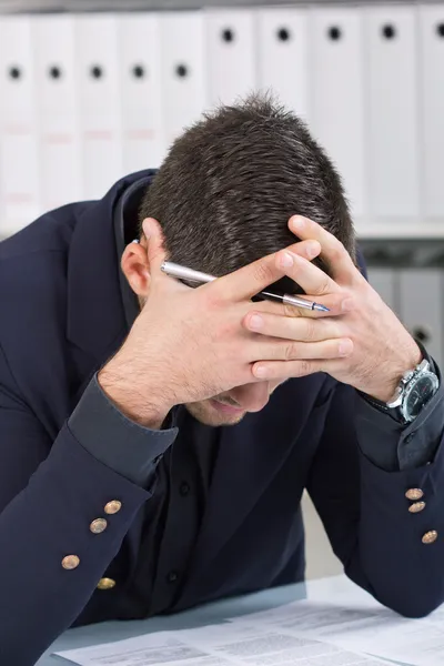 Bezorgd zakenman in donker pak aan bureau zitten — Stockfoto