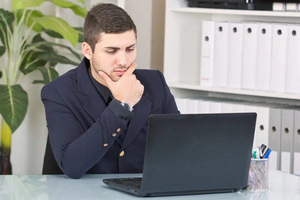 Jungunternehmer schaut auf den Laptop — Stockfoto