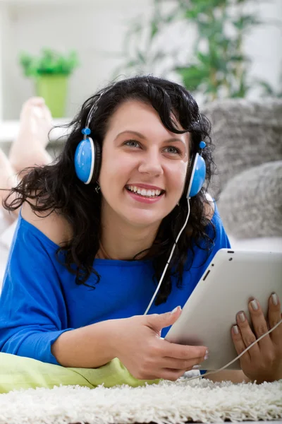 Joven mujer sonriente con tableta y auriculares en casa — Foto de Stock